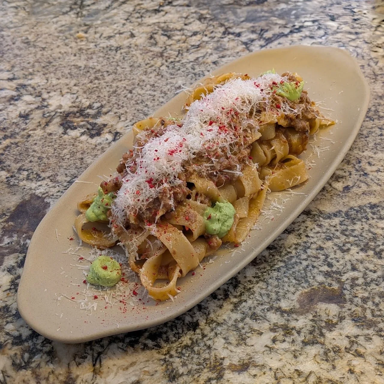 A plate of pasta with a creamy sauce and herb garnish