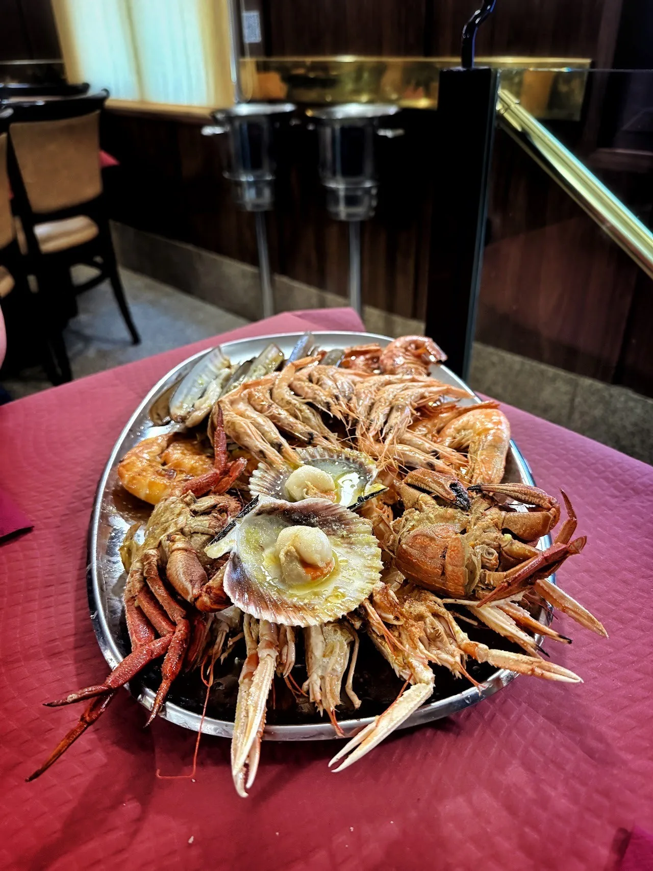 A platter of shellfish and scallops on a red tablecloth