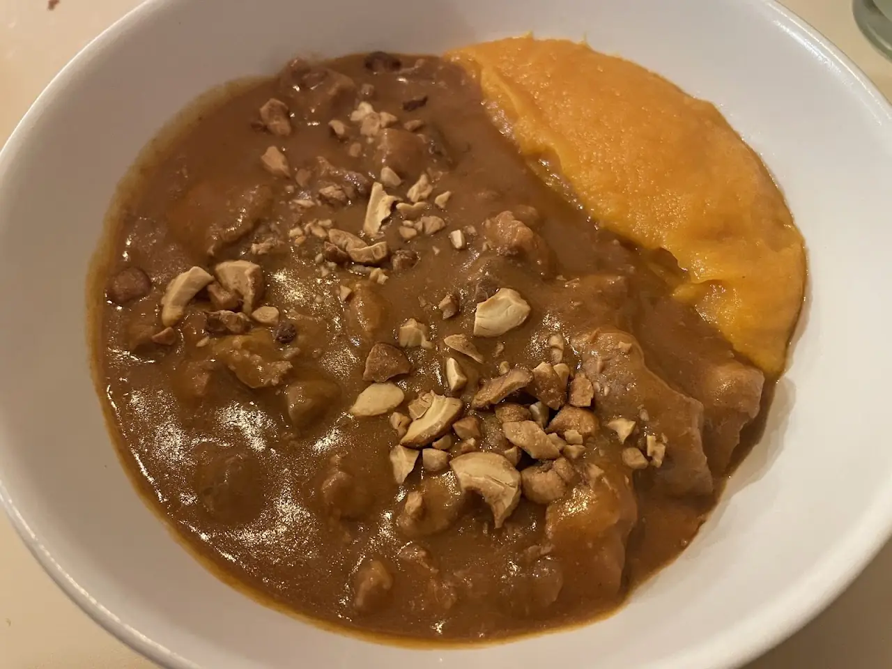 Braised meat stew with a squash purée and chopped nuts on a white plate, at Market Cuina Fresca.