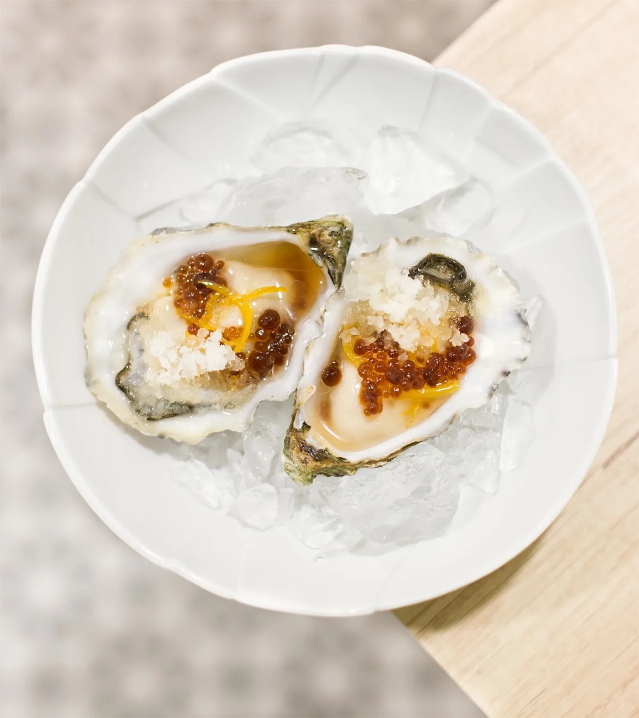 Two oysters topped with a spiced sauce on ice