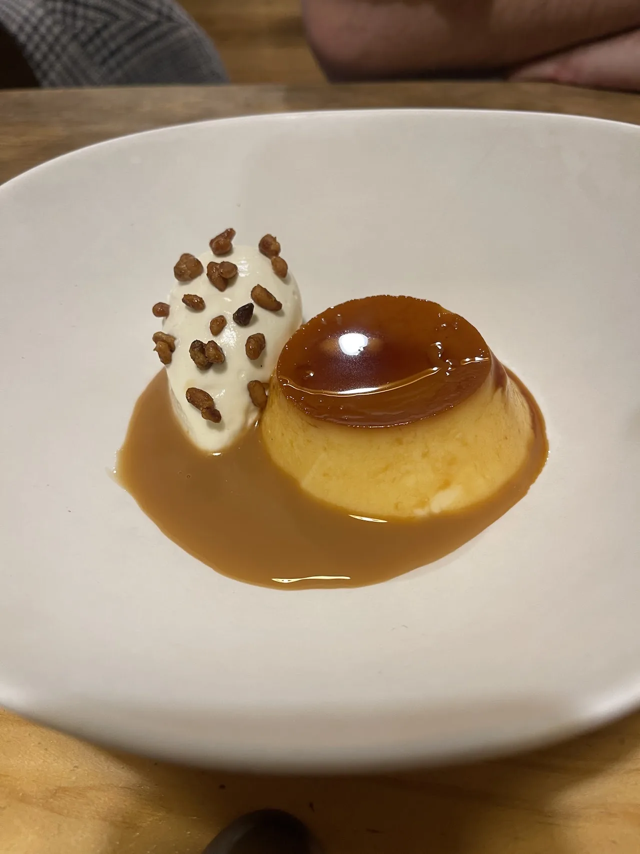 A flan dessert with caramel sauce and almond garnish