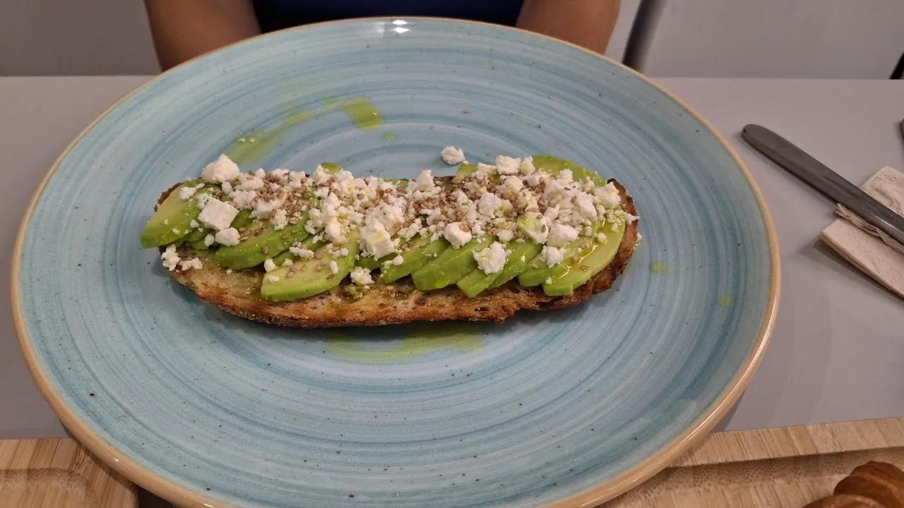 An open-face avocado toast topped with crumbled cheese