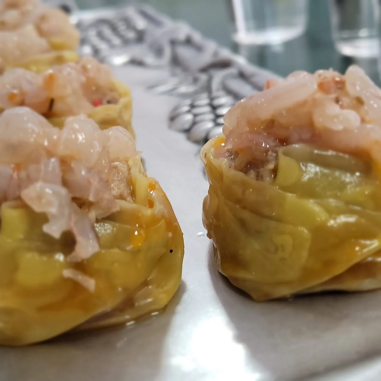Two siu mai dumplings topped with shrimp