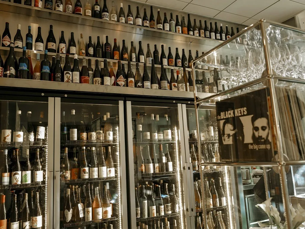Glass-fronted fridges filled with wine bottles along a wall
