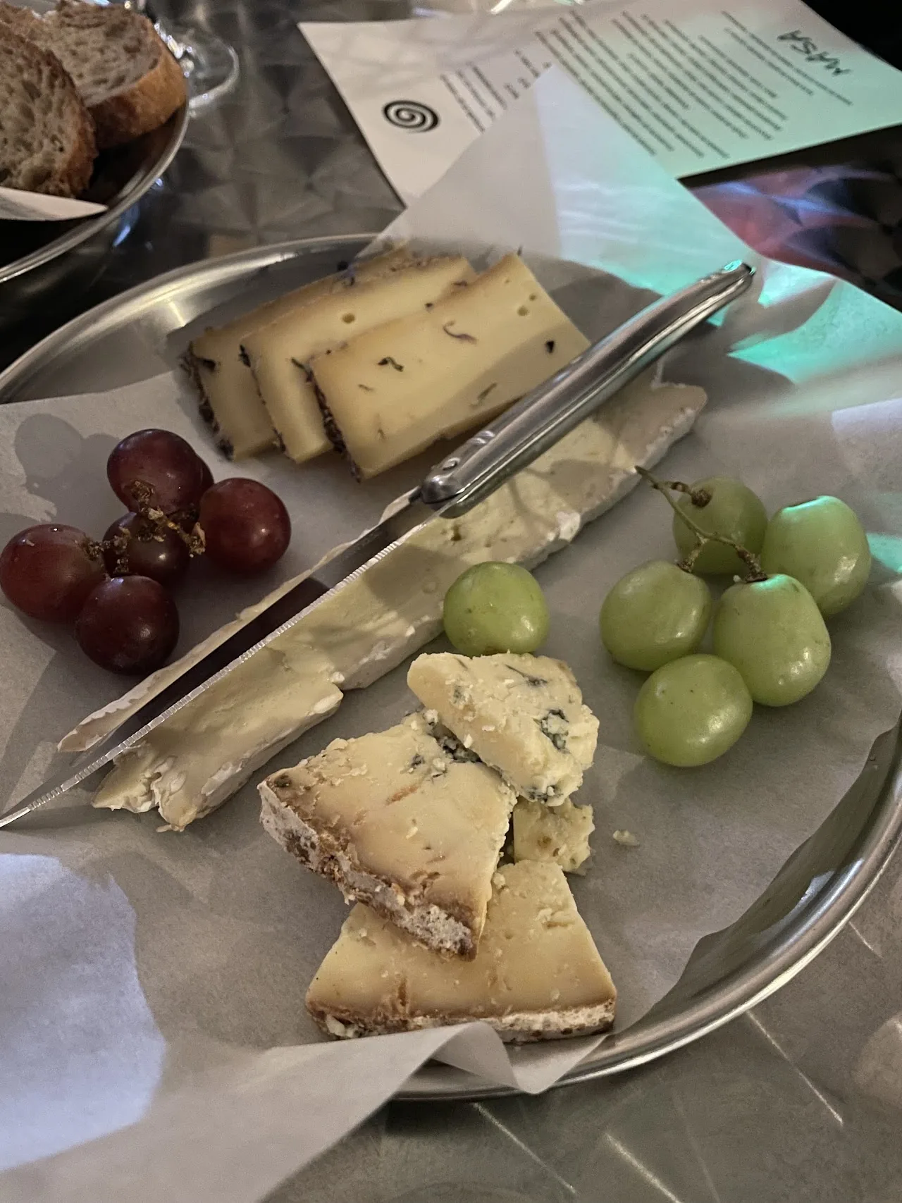A cheese board with sliced cheese and grapes