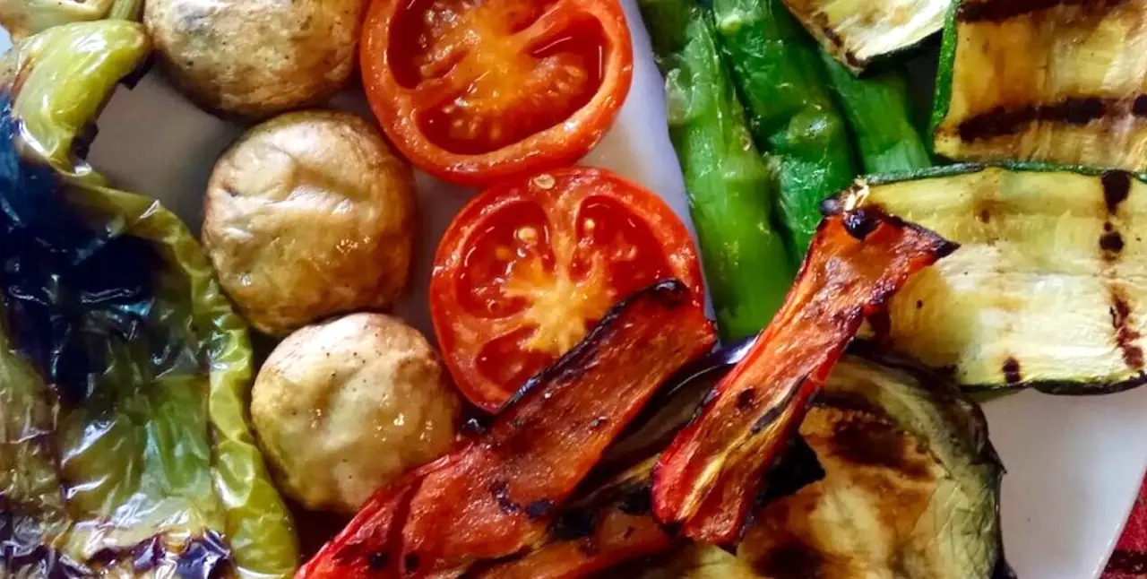 Grilled mixed vegetables — mushrooms, halved tomatoes, green peppers, zucchini, and red pepper strips with char marks — plated at Restaurant Masia Can Jané