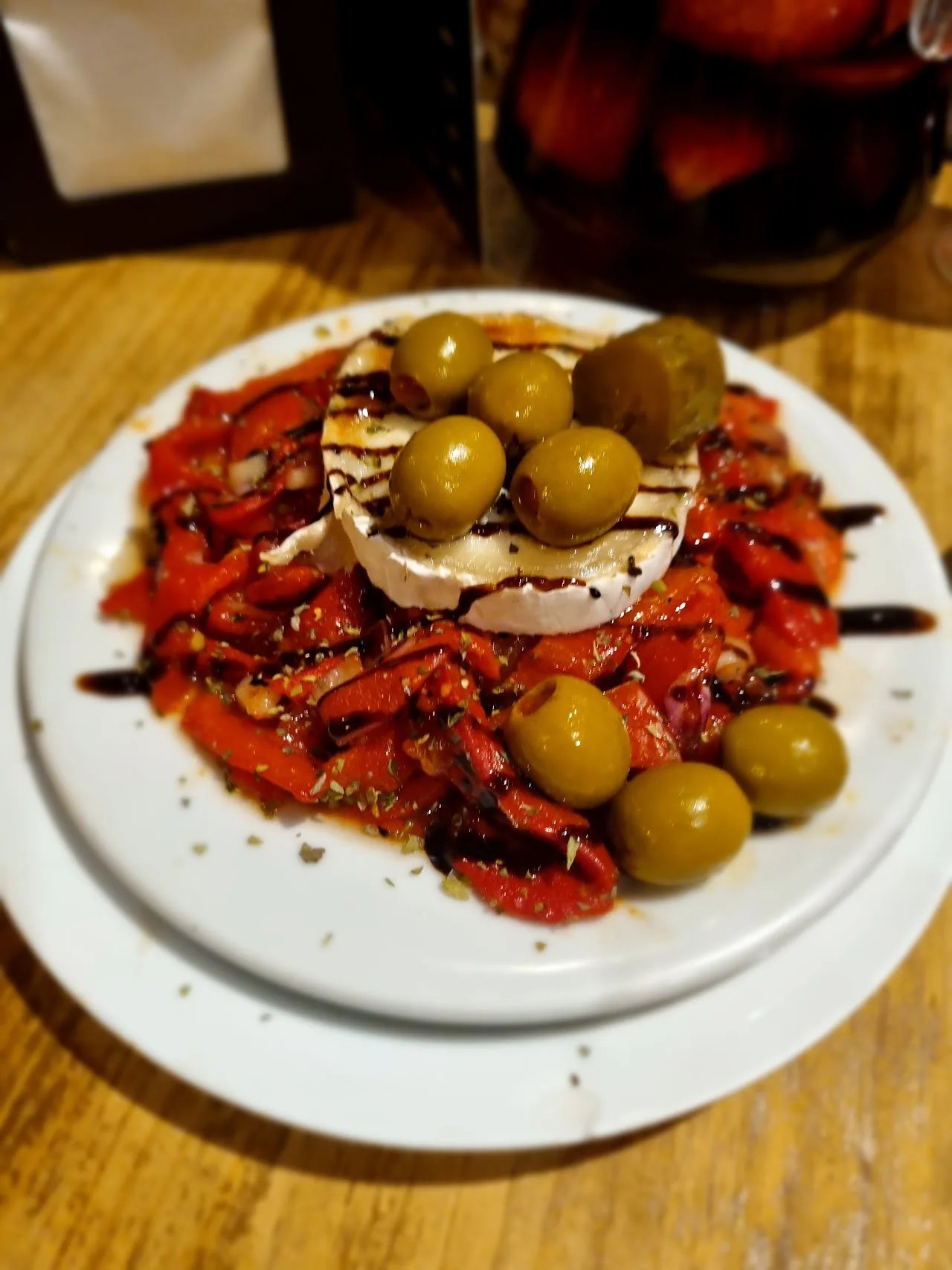 A plate of marinated goat cheese with roasted red peppers and olives