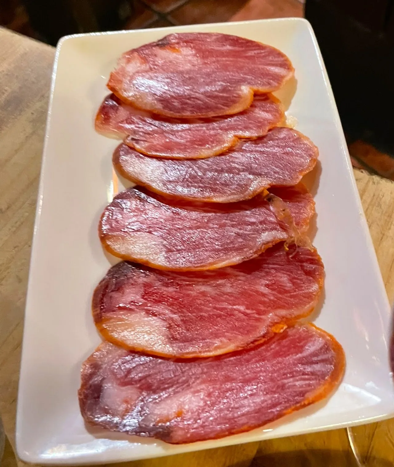 Thin slices of cured Iberian sausage arranged on a plate