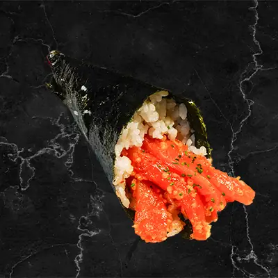 Spicy tuna temaki hand roll in nori cone with rice on a dark marble surface