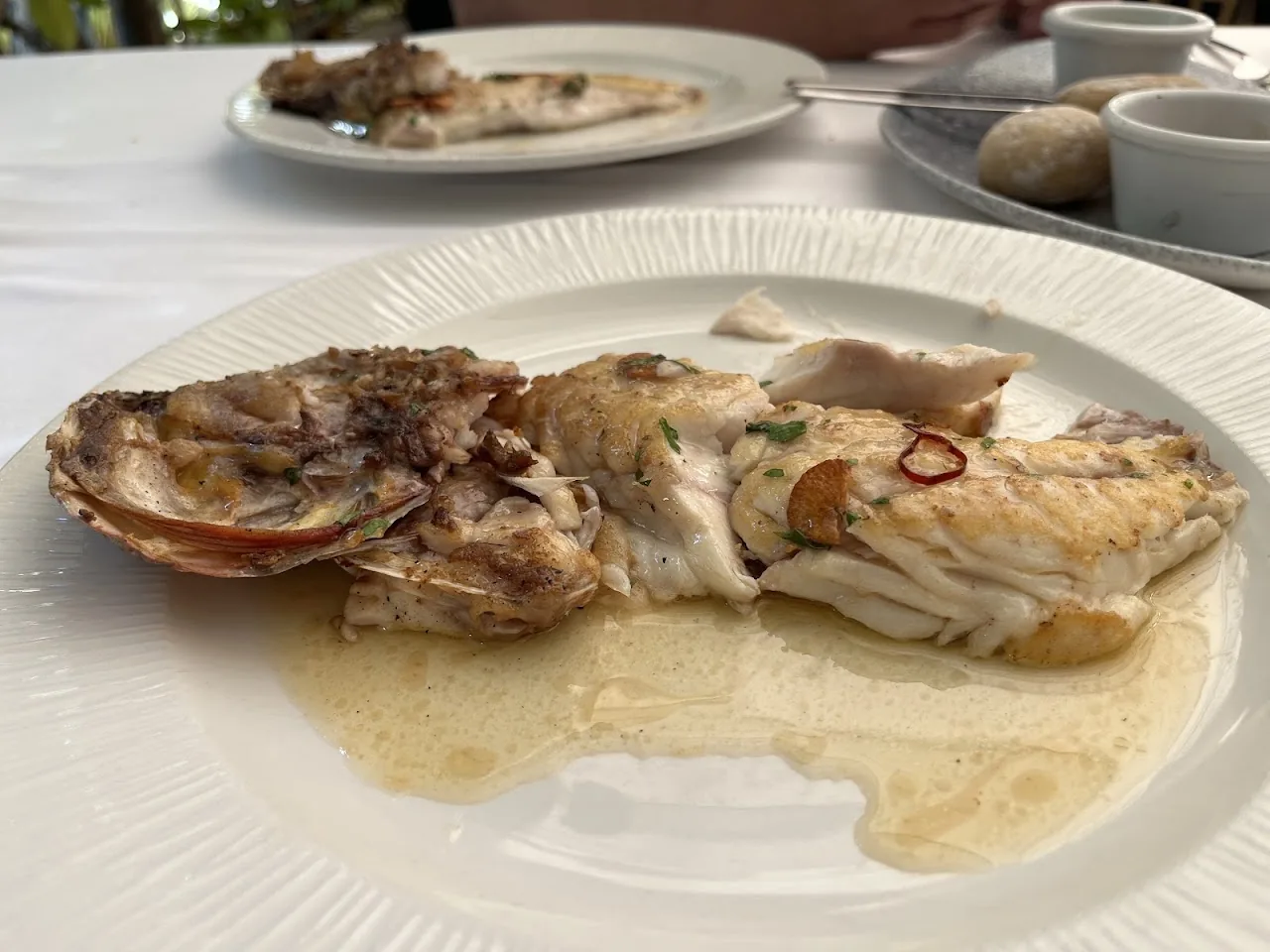 A whole grilled fish fillet with clams in a green sauce