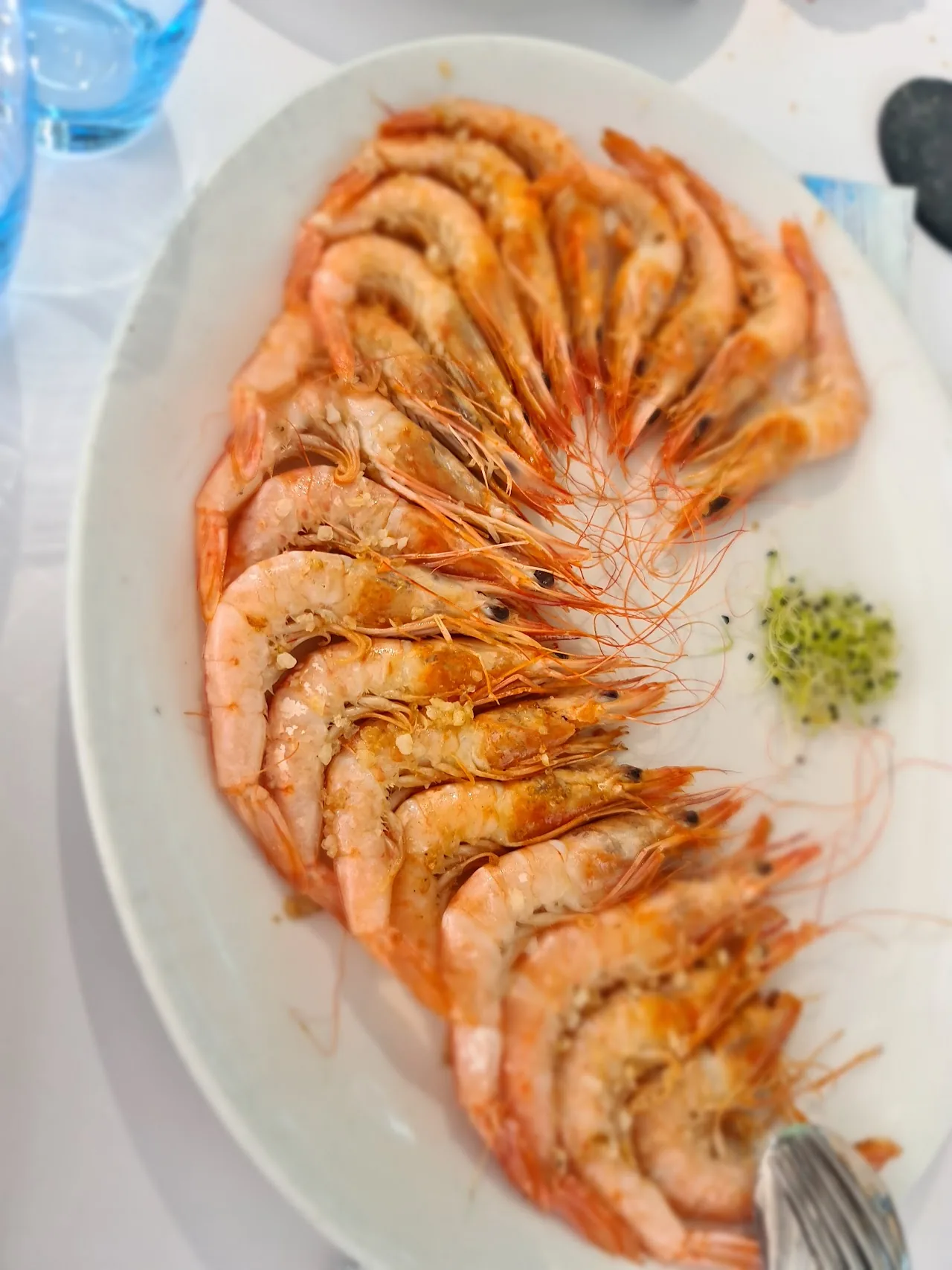 A plate of grilled whole prawns with a dollop of green sauce