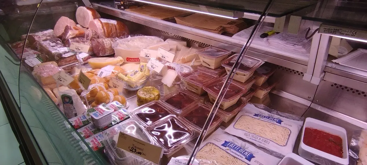 Deli case with cured meats, cheeses, tiramisu and prepared sauces