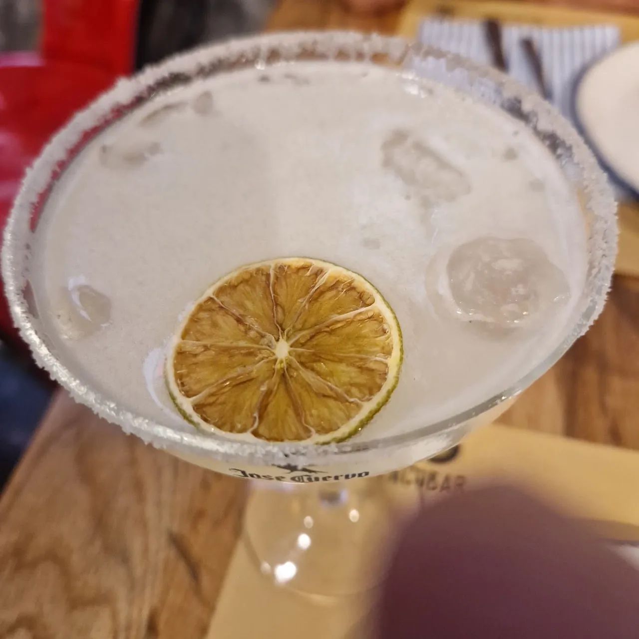 A salt-rimmed margarita garnished with a dried lime wheel