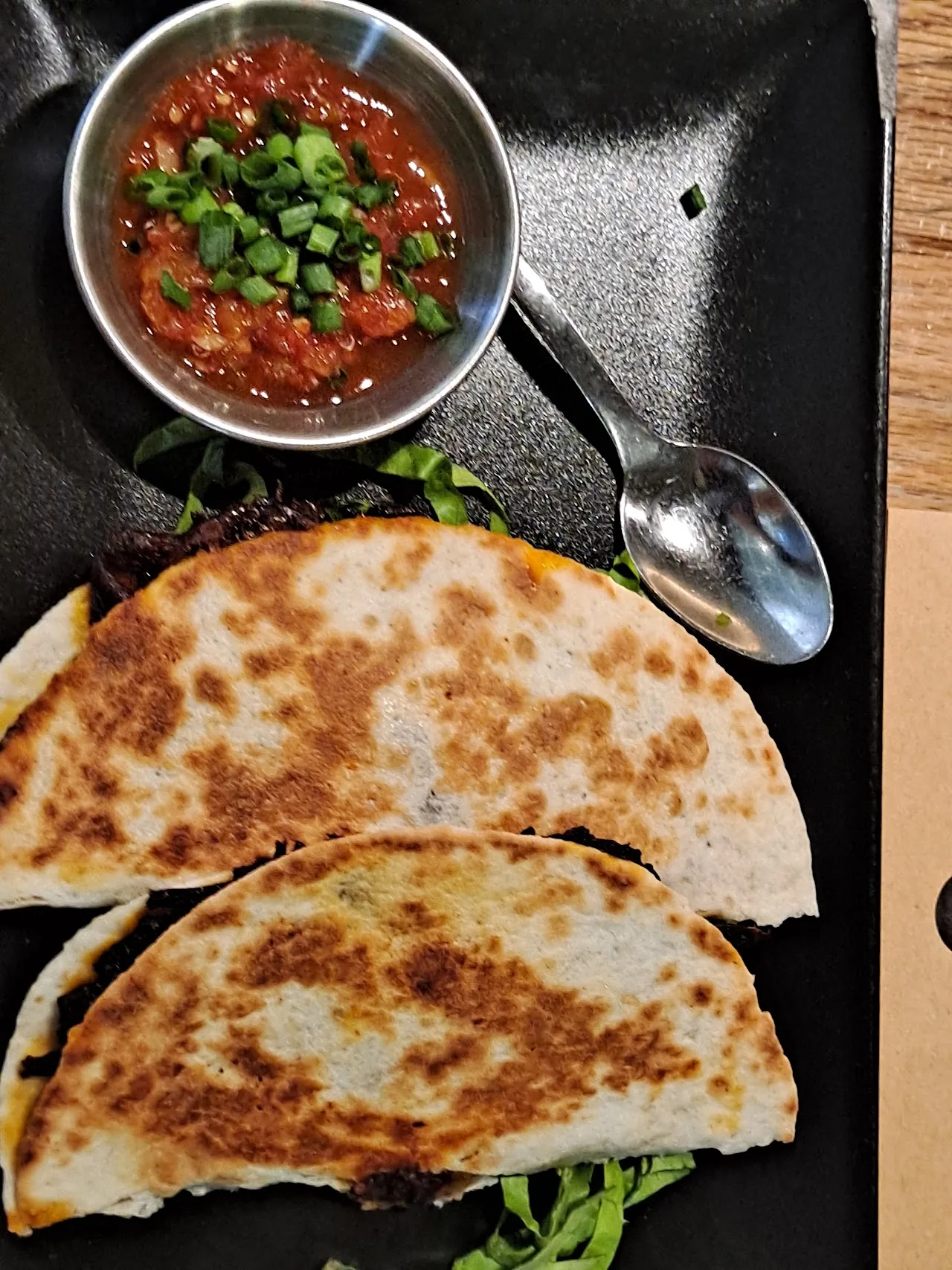 Folded quesadillas on a plate with a bowl of red salsa