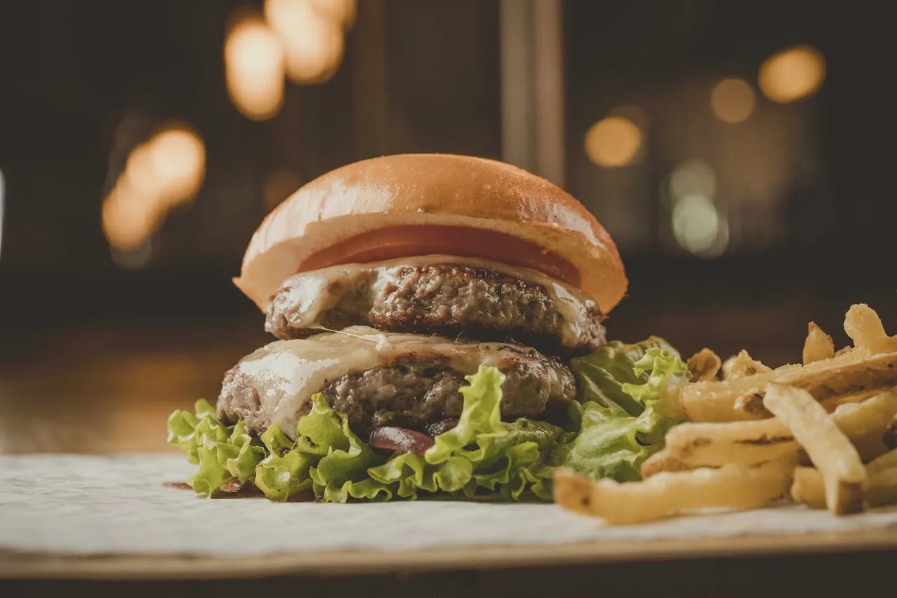 A double stacked burger with lettuce and fries in the background
