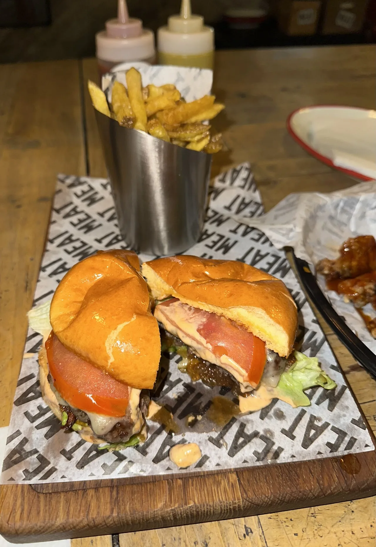 Sandwiches stacked on a board with a side of fries in a metal cup