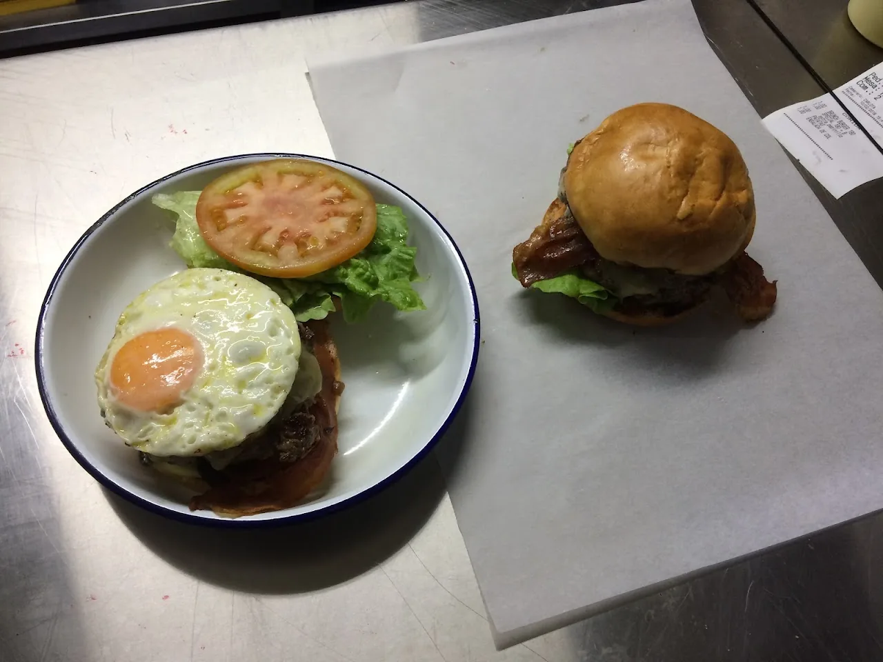 A fried egg burger next to a classic burger on a white plate