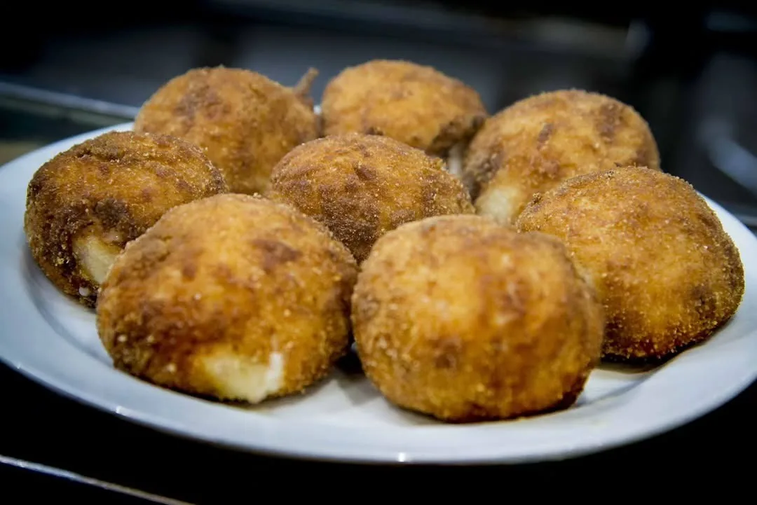 Six golden fried croquettes on a white plate