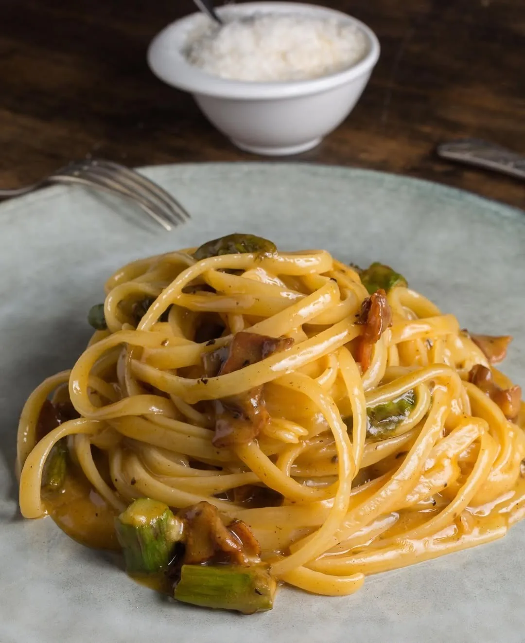 A plate of spaghetti with green vegetables and a light sauce