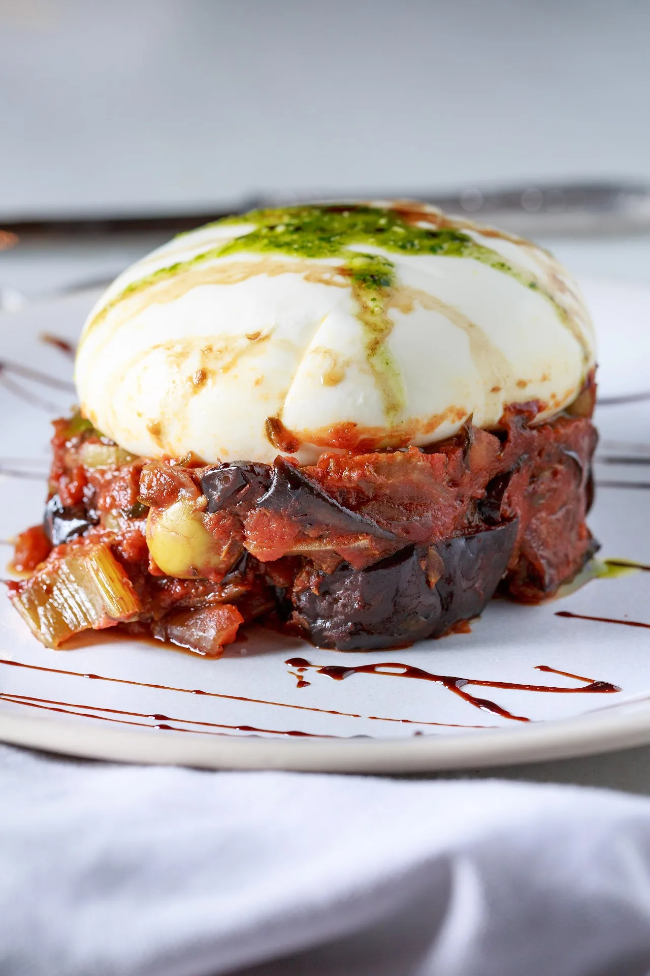 A burrata cheese ball on top of a diced tomato and eggplant caponata