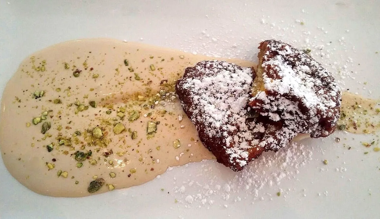A chocolate dessert dusted with powdered sugar over a sauce swirl