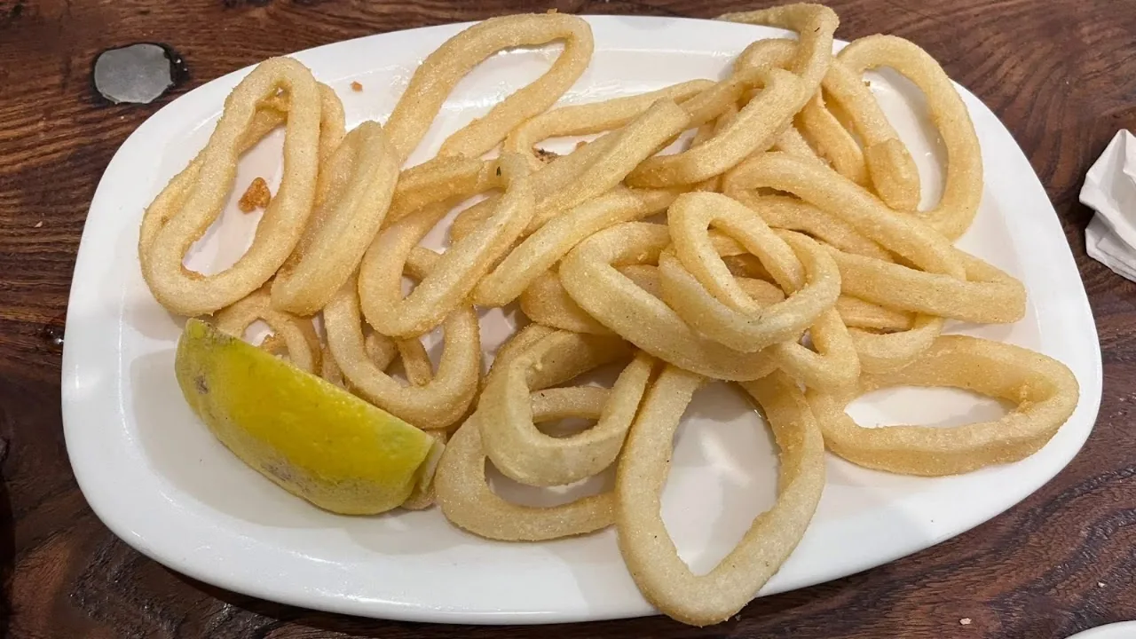 A plate of fried calamari rings with a lemon wedge