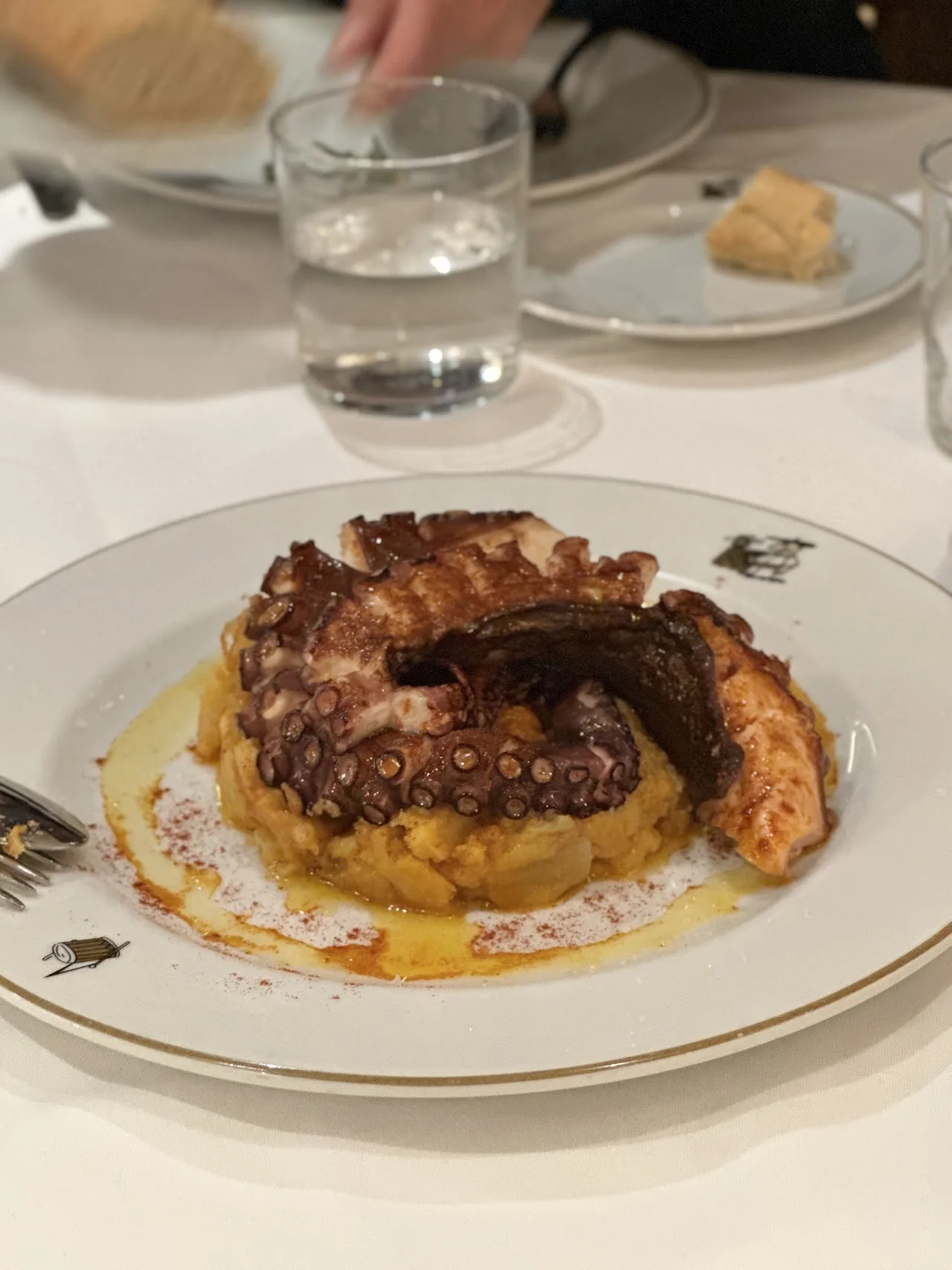 A piece of octopus on mashed potato on a white plate