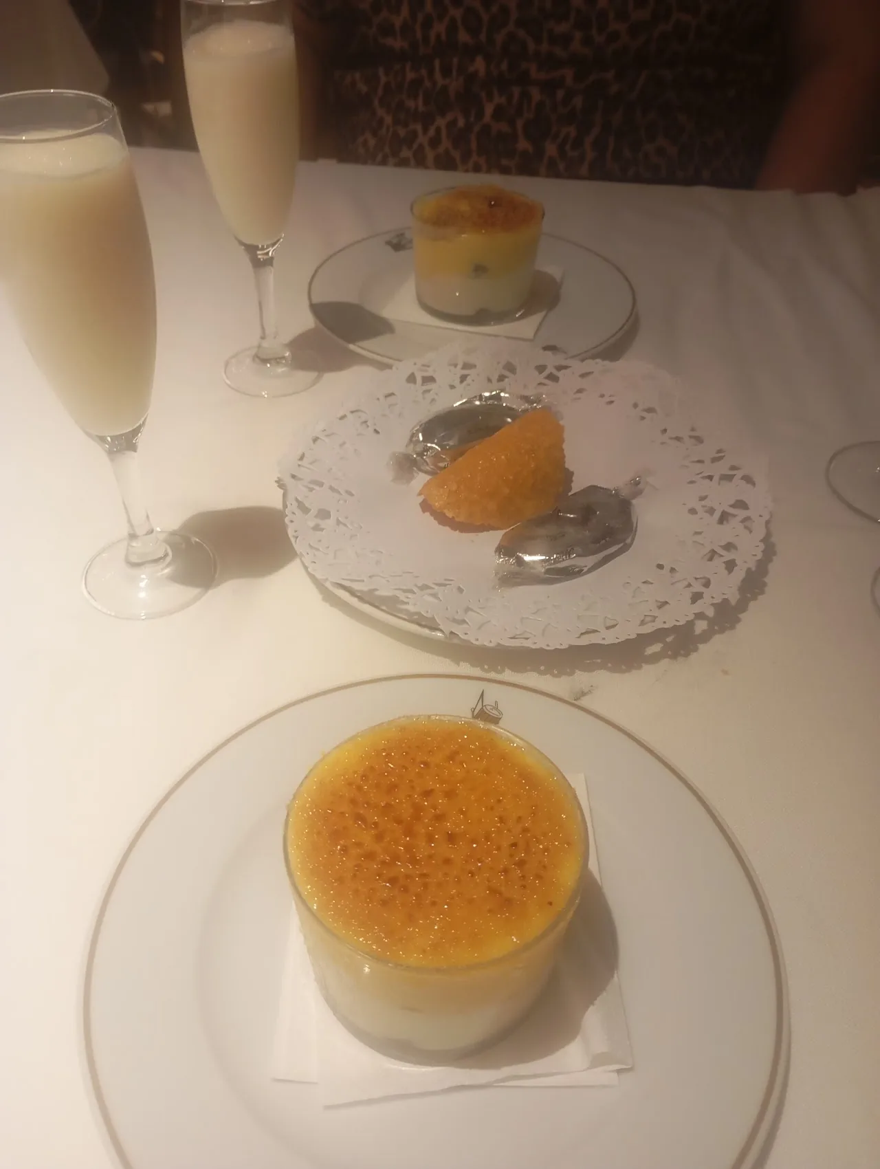 A crème brûlée and dessert plate served with glasses of sparkling wine