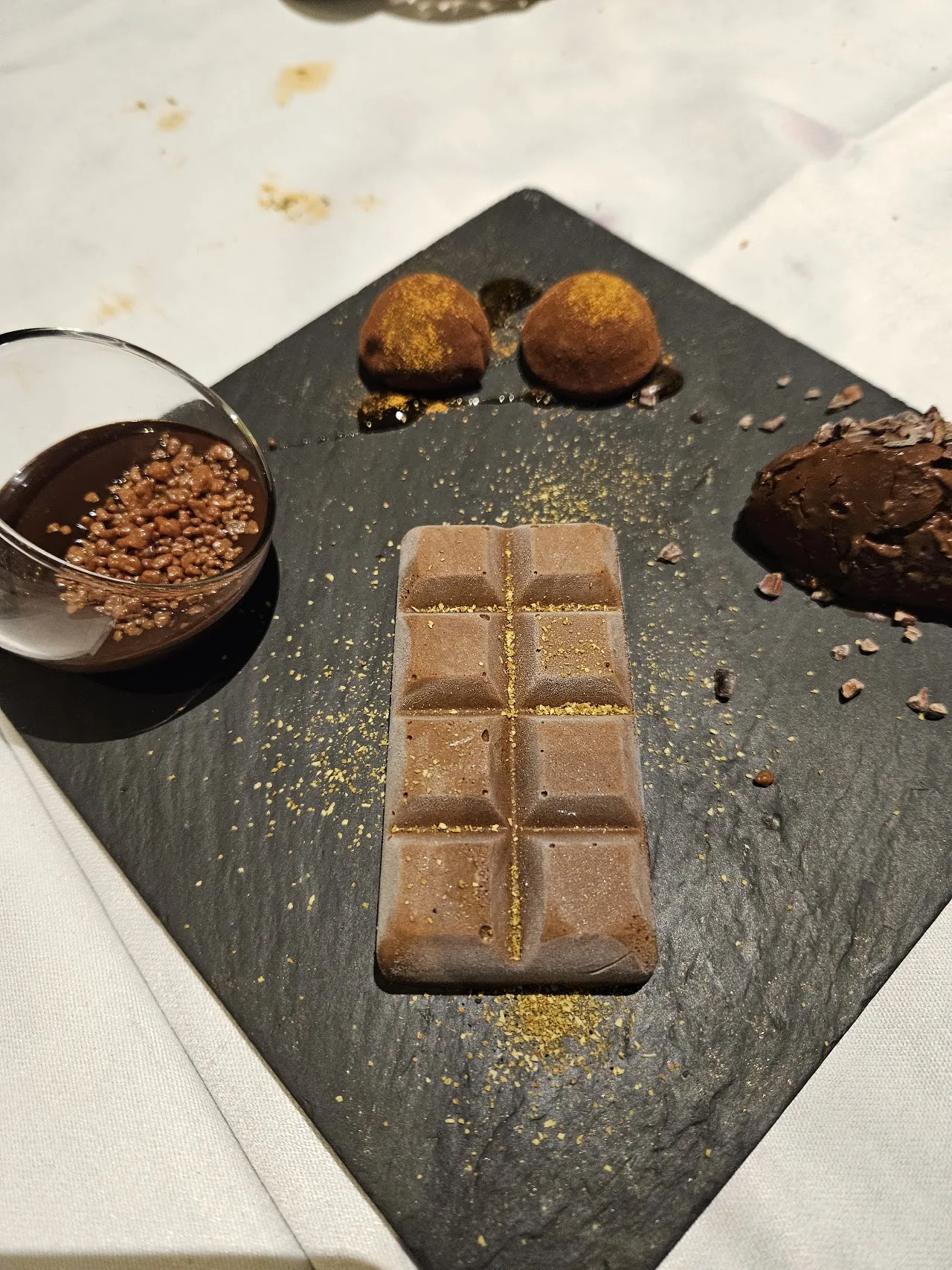 A dessert plate with two chocolate mousse quenelles and a caramel square