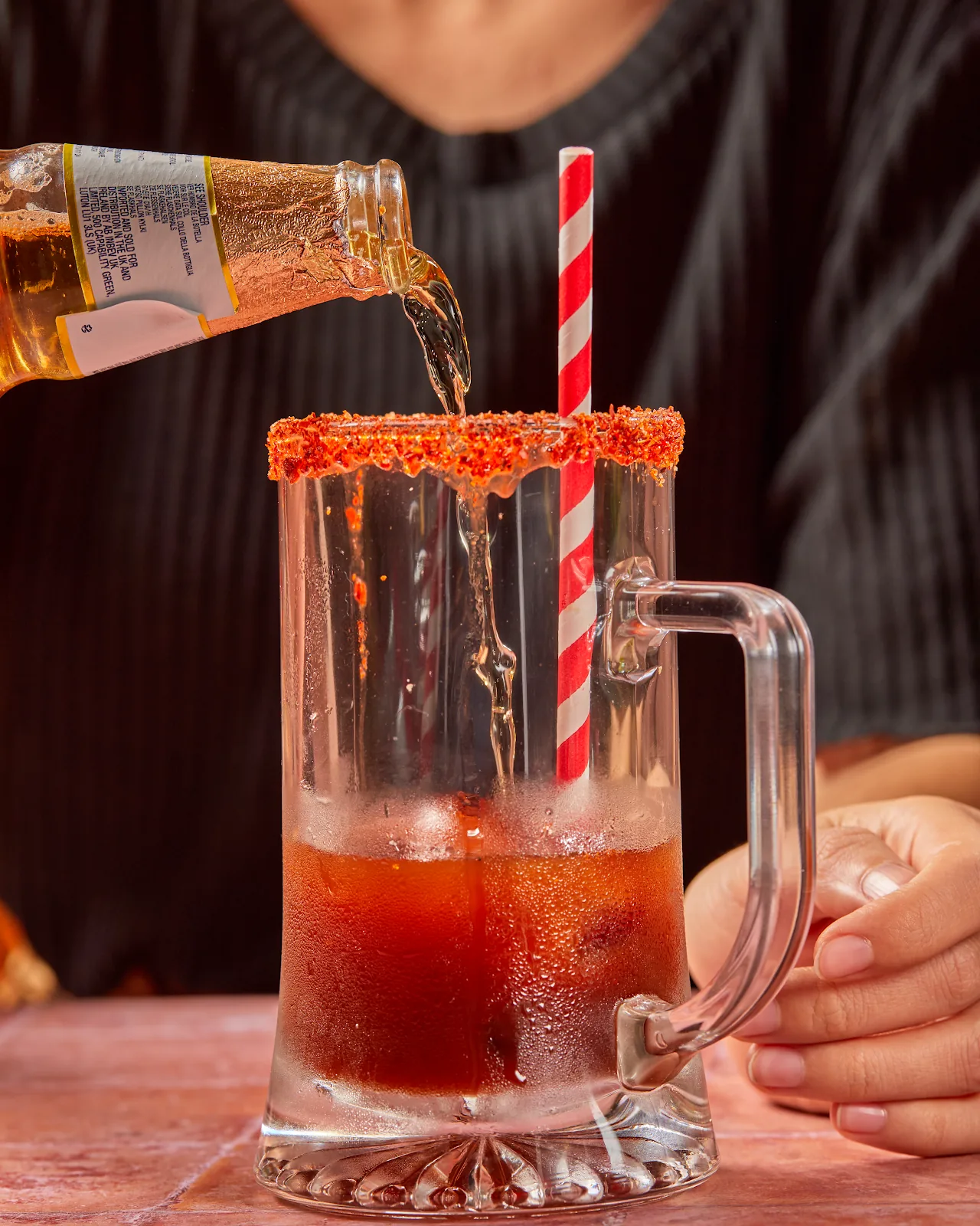 A tamarind cocktail with a red-rimmed glass and striped straw