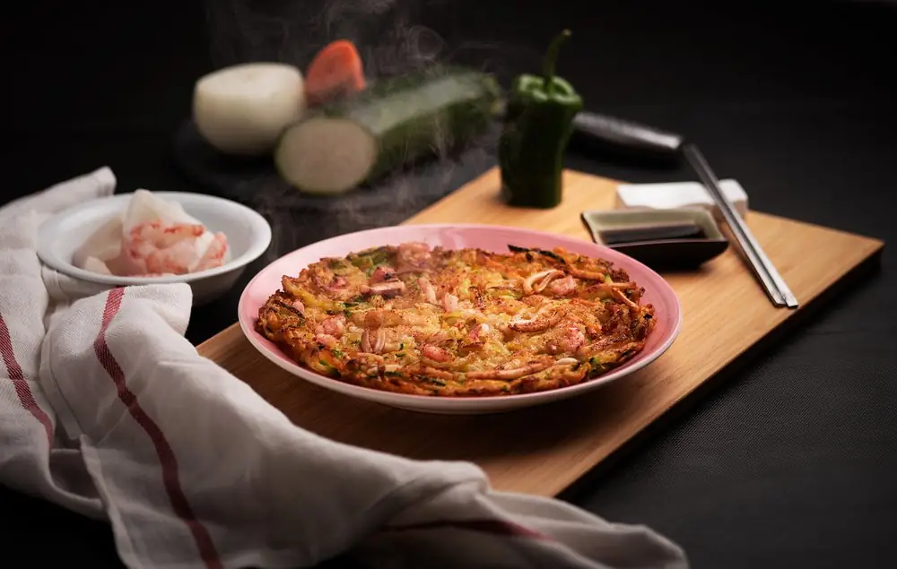 A seafood pancake on a pink plate on a wooden board