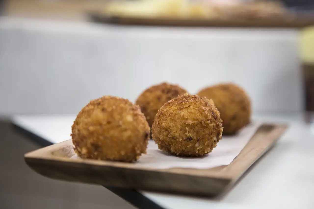 Three breaded croquettes on a wooden board.