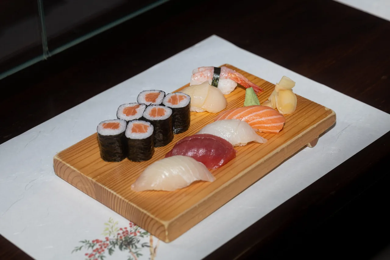 A wooden board of nigiri and maki sushi on a white cloth