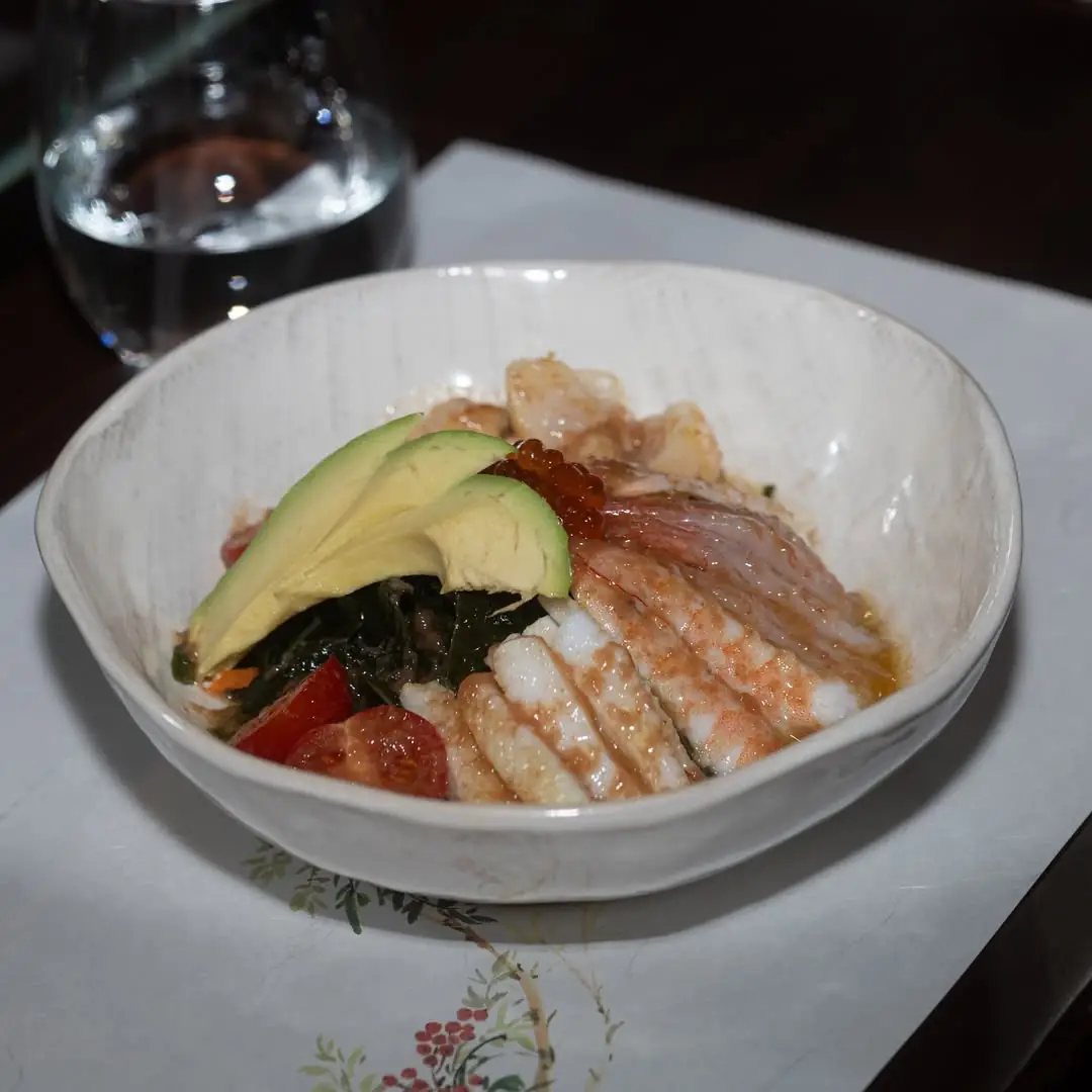 Seafood rice bowl topped with avocado slices, salmon roe, shrimp and cherry tomatoes