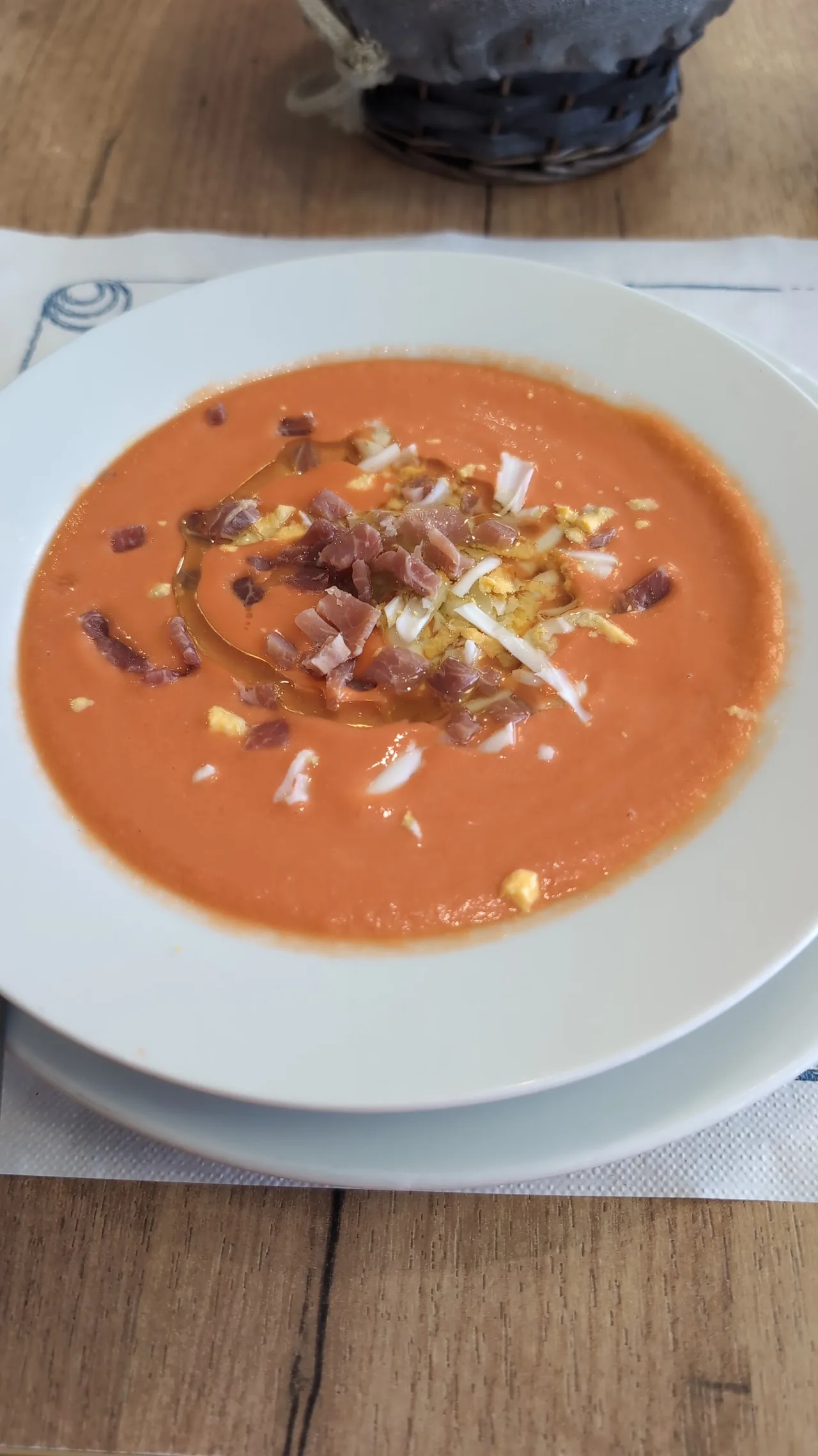 A bowl of orange soup topped with croutons and herbs