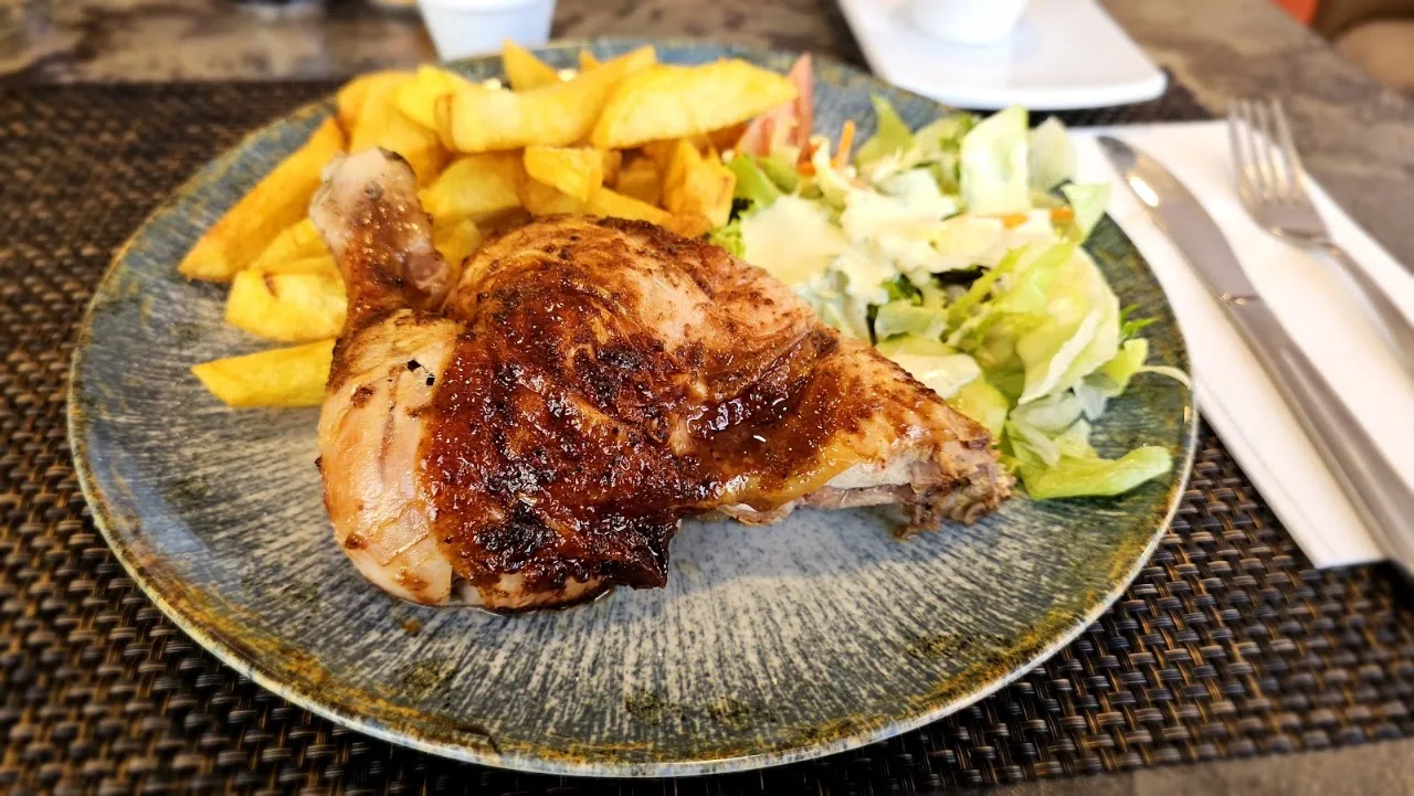 A grilled chicken quarter plate with fries and salad