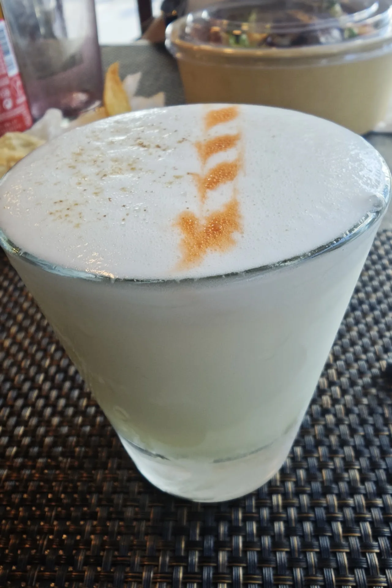 A pisco sour cocktail with a frothy top and cinnamon dust
