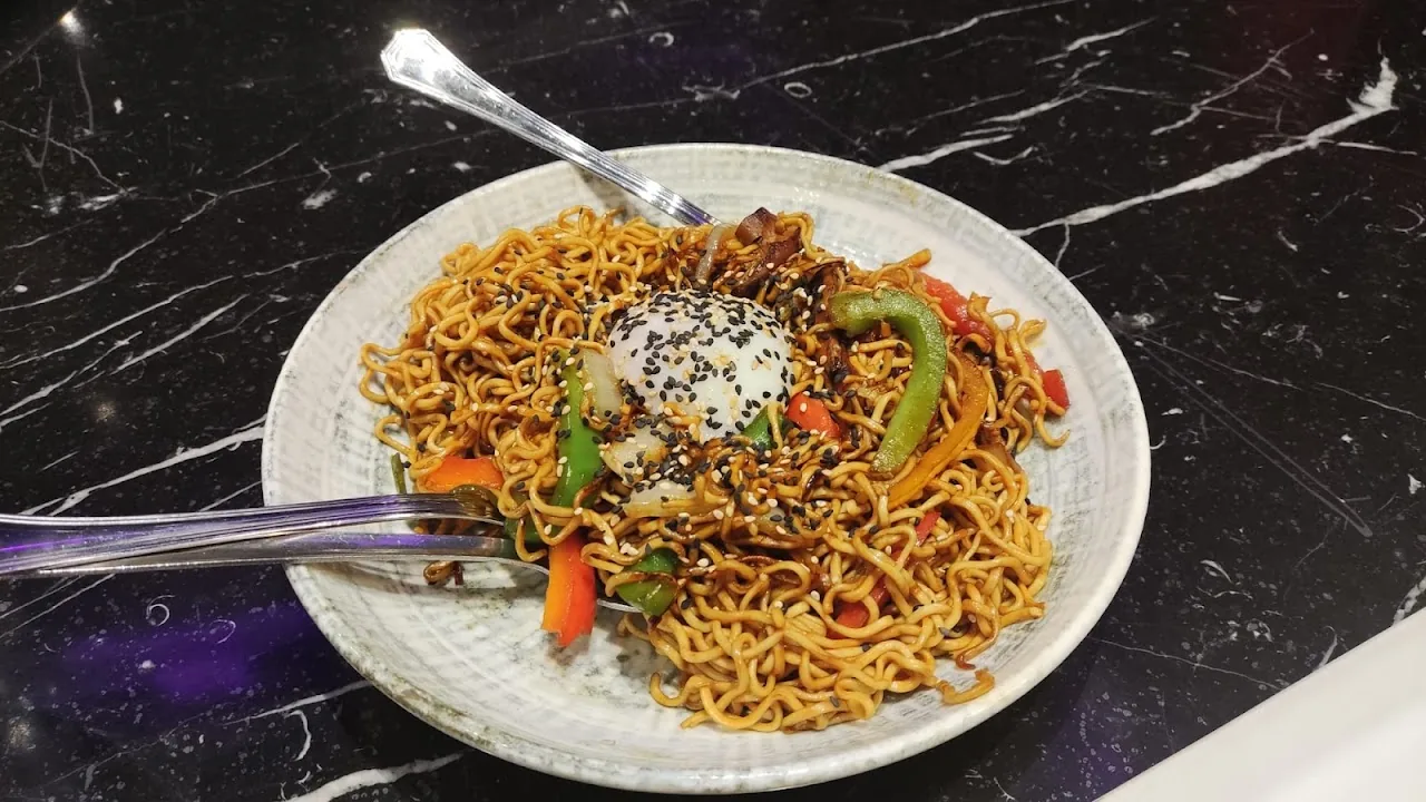 A plate of noodles topped with vegetables and a fried egg