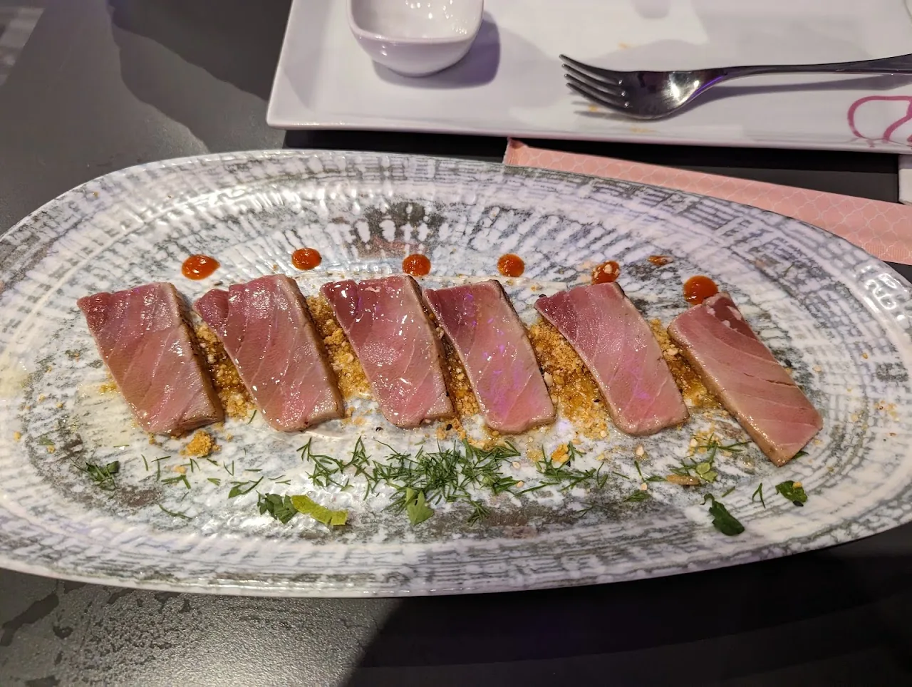 A row of seared tuna slices arranged on an oval plate