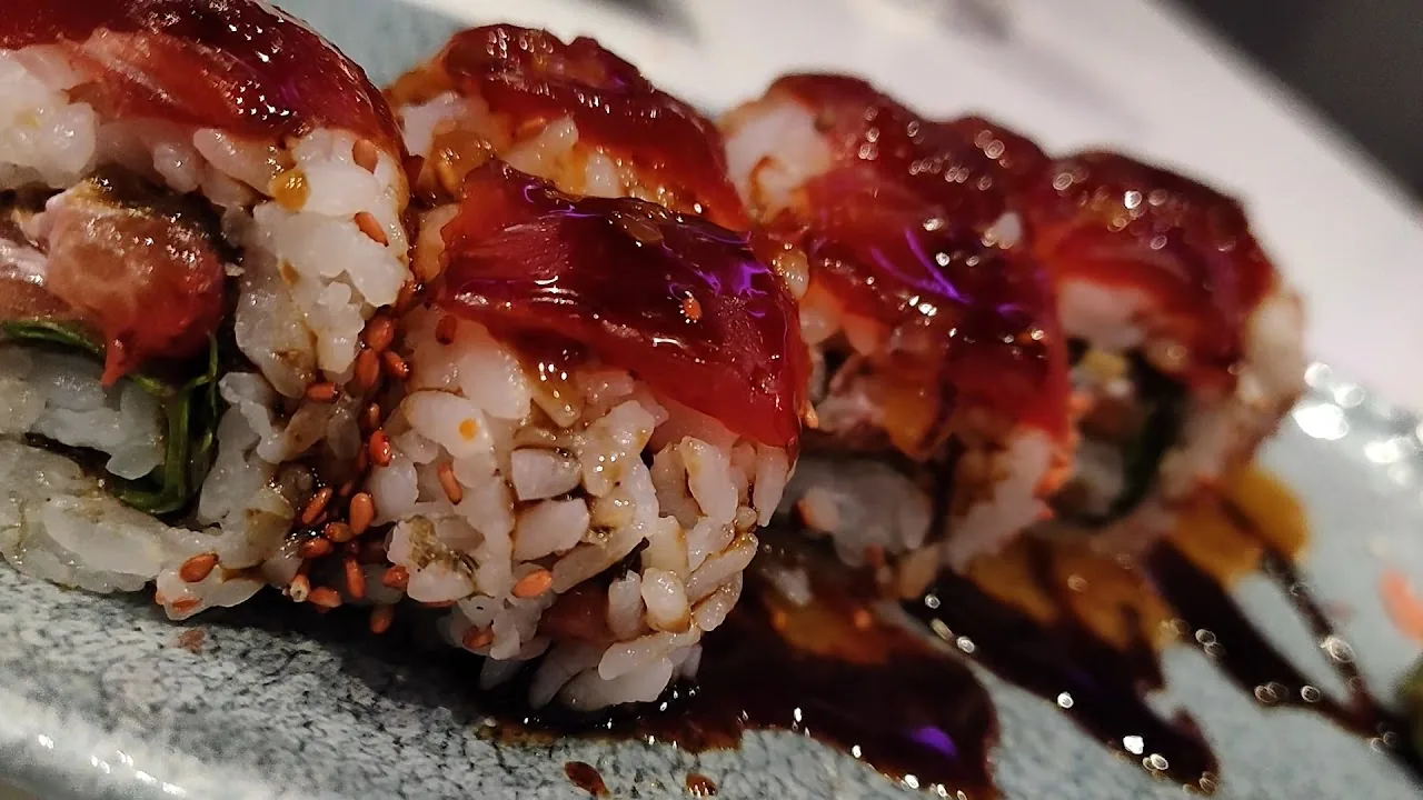 Sushi rolls topped with tuna and drizzled with sauce