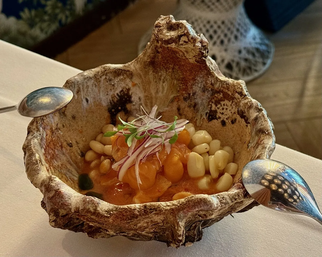 A shell-shaped bowl with white beans, onion, and orange sauce