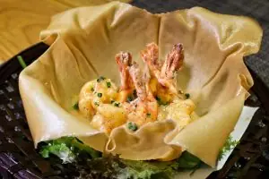 Tempura shrimp served in a fried wonton basket over greens