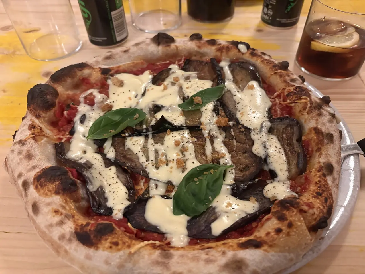 Wood-fired pizza topped with grilled eggplant, melted cheese and basil leaves