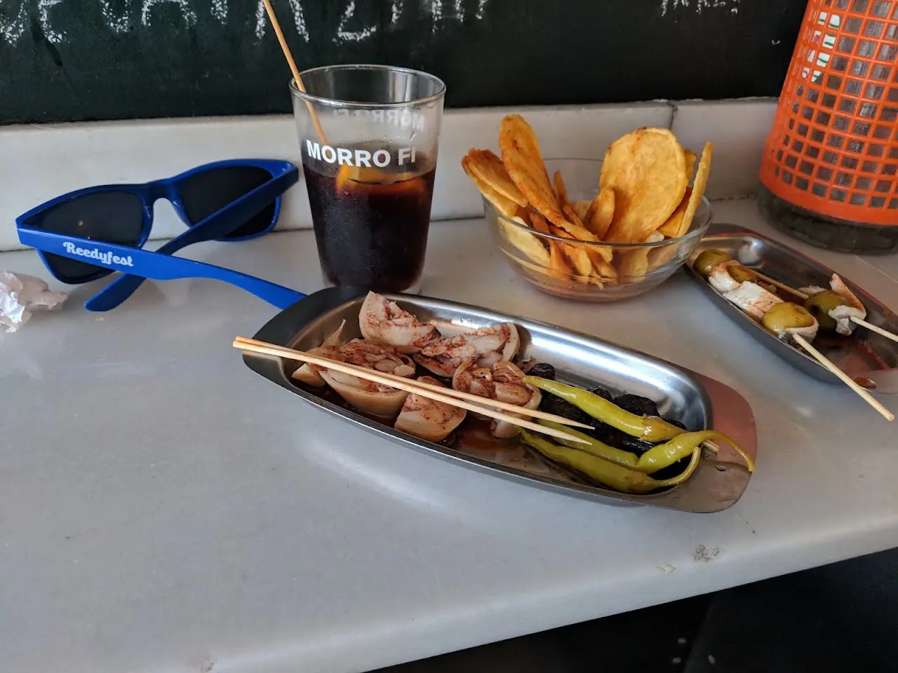 Tin of tinned seafood with a skewer, crisps and a vermouth on a marble counter, at Morro Fi.