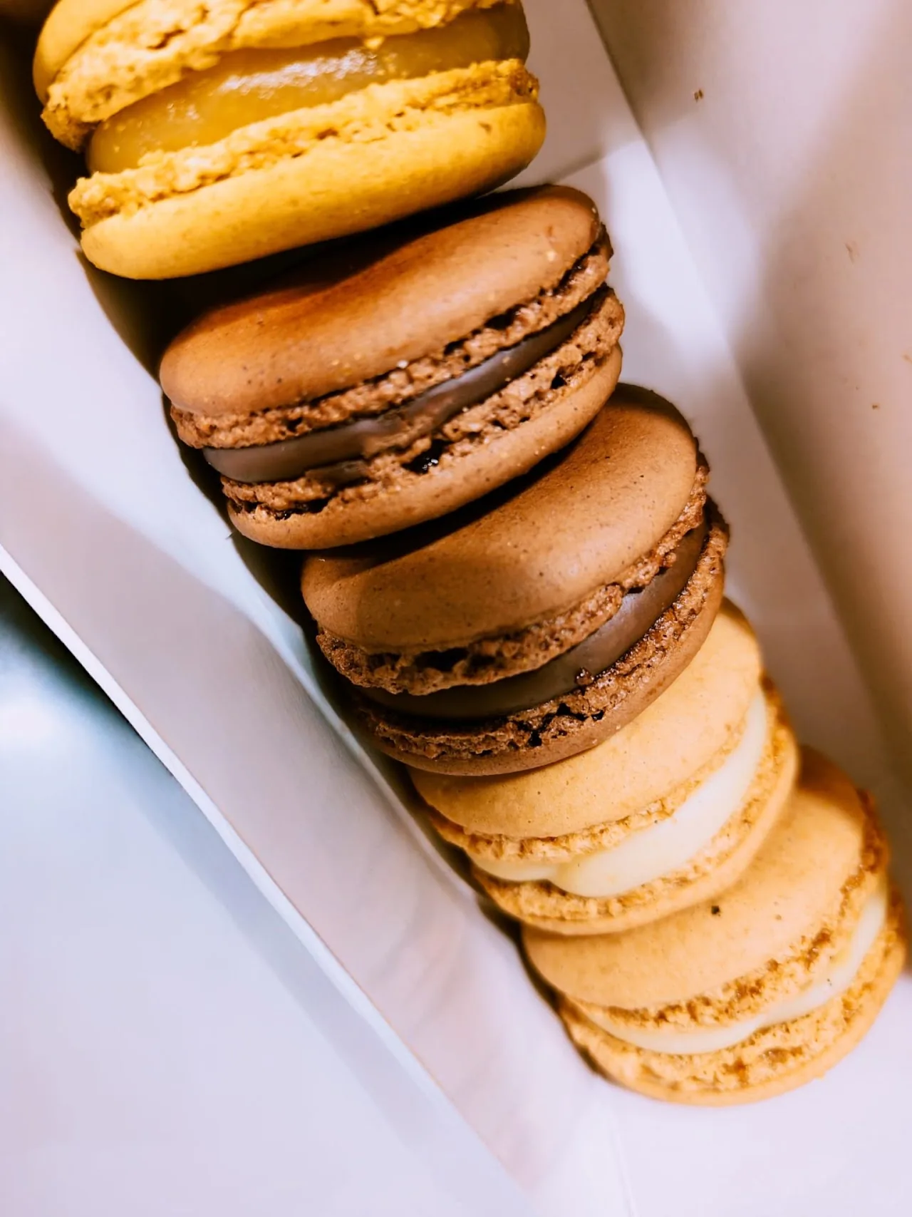 A stack of colorful macarons in a takeaway box