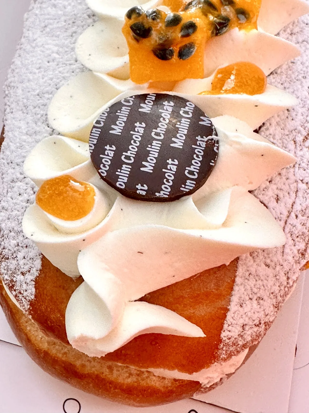 A layered cake topped with whipped cream, passion fruit, and citrus