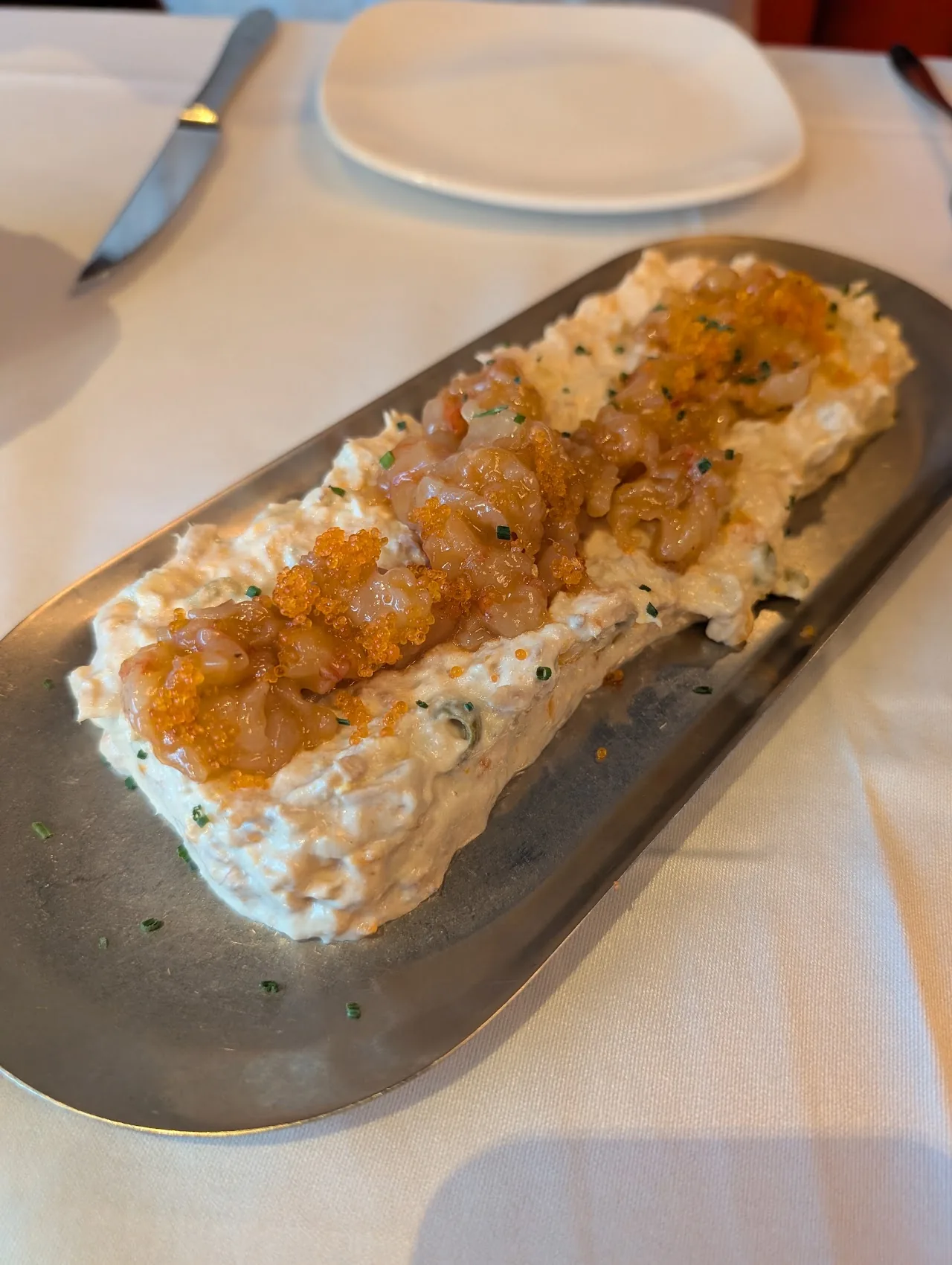 A creamy seafood dish on a metal serving tray