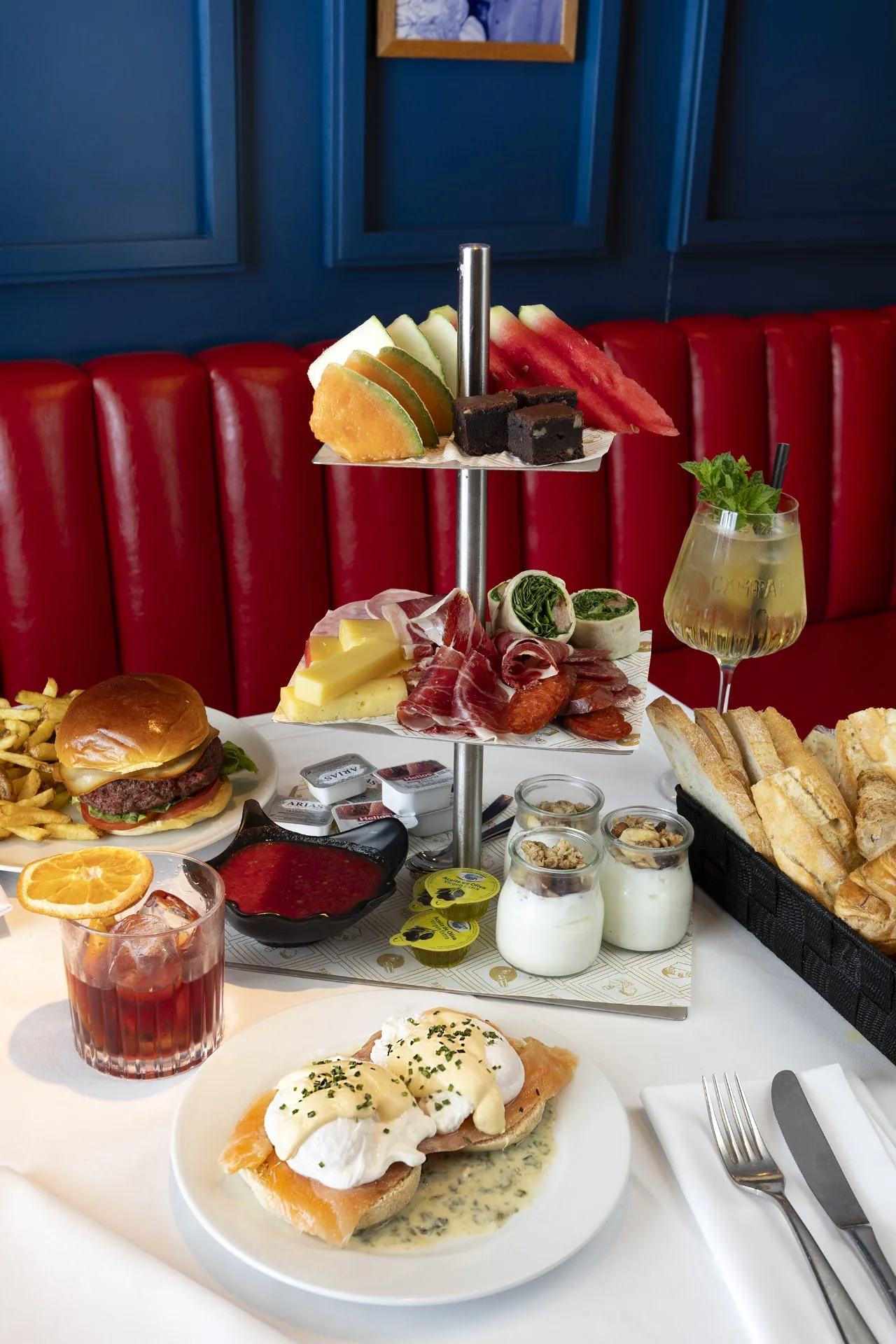 A tiered stand with tea sandwiches, scones, and mini desserts alongside a burger