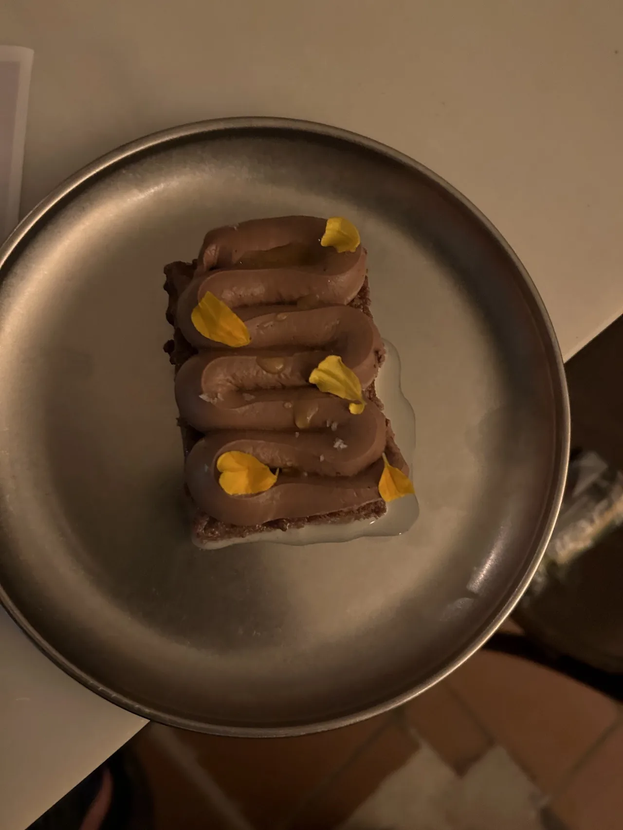Slices of a rich spread arranged in a row on a dark round plate