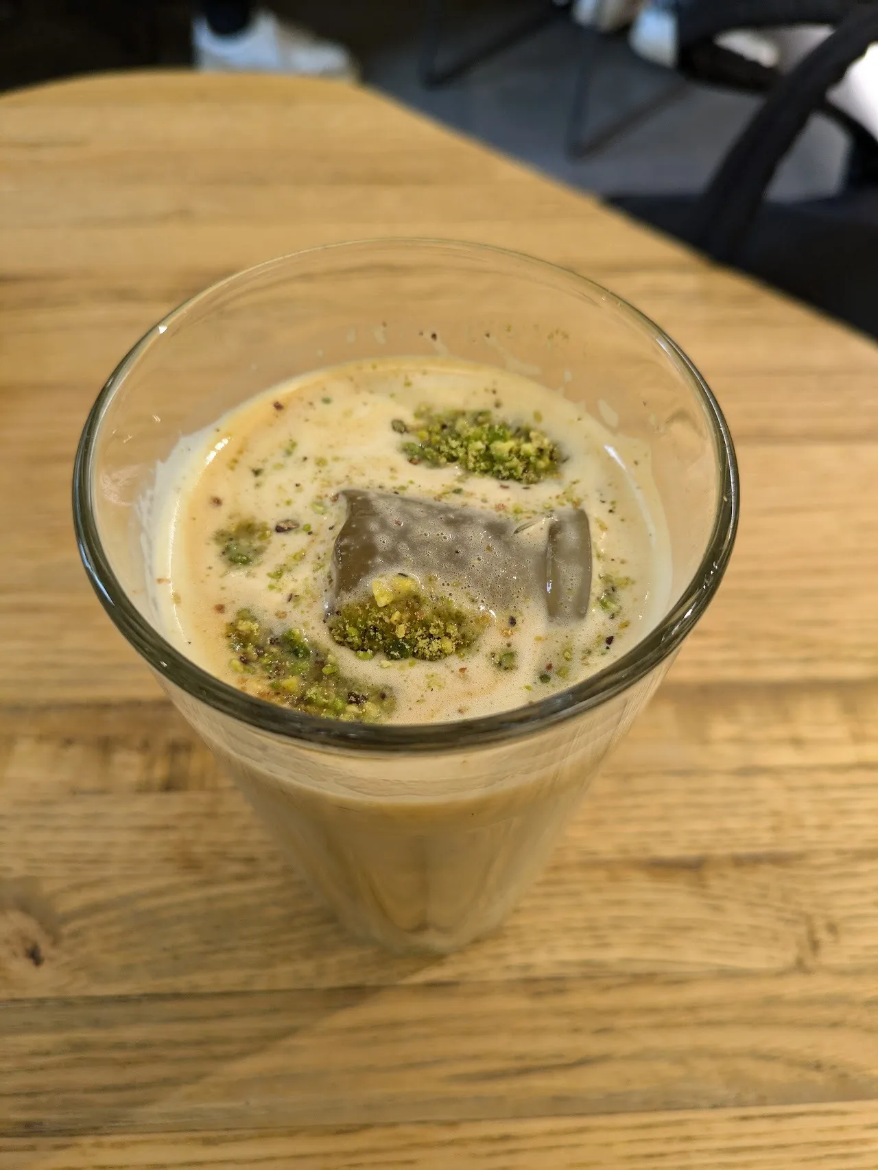 An iced coffee drink in a glass topped with chopped pistachio